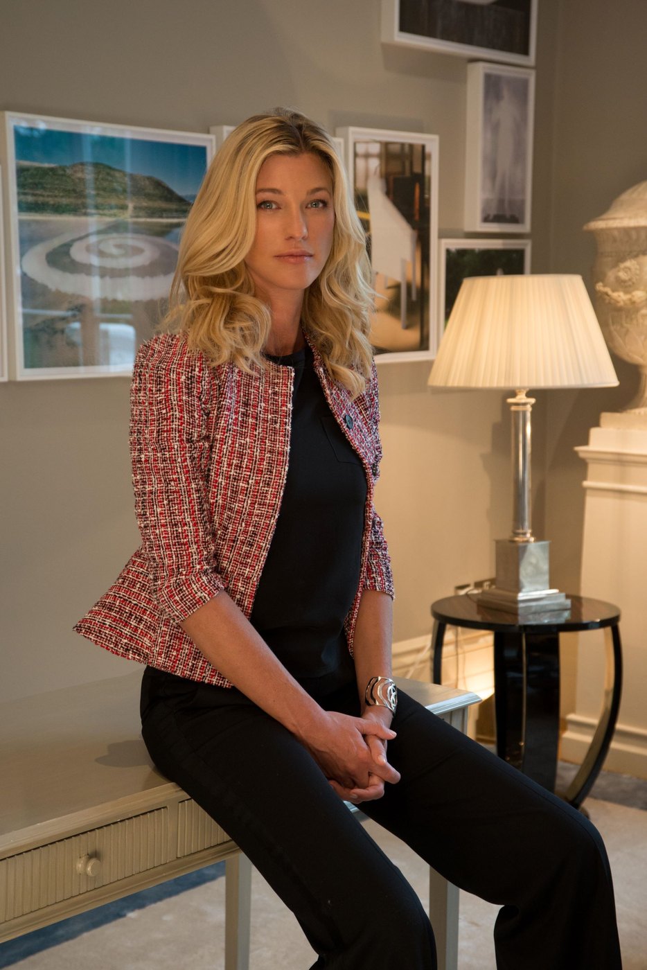 Nicole Brachetti Peretti seated in a room hung with framed works, wearing a tweed jacket